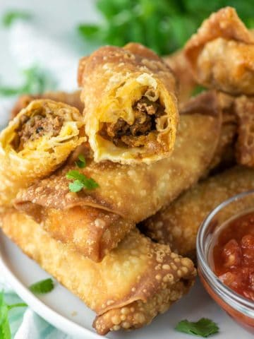 taco egg roll cut in half on top of other egg rolls