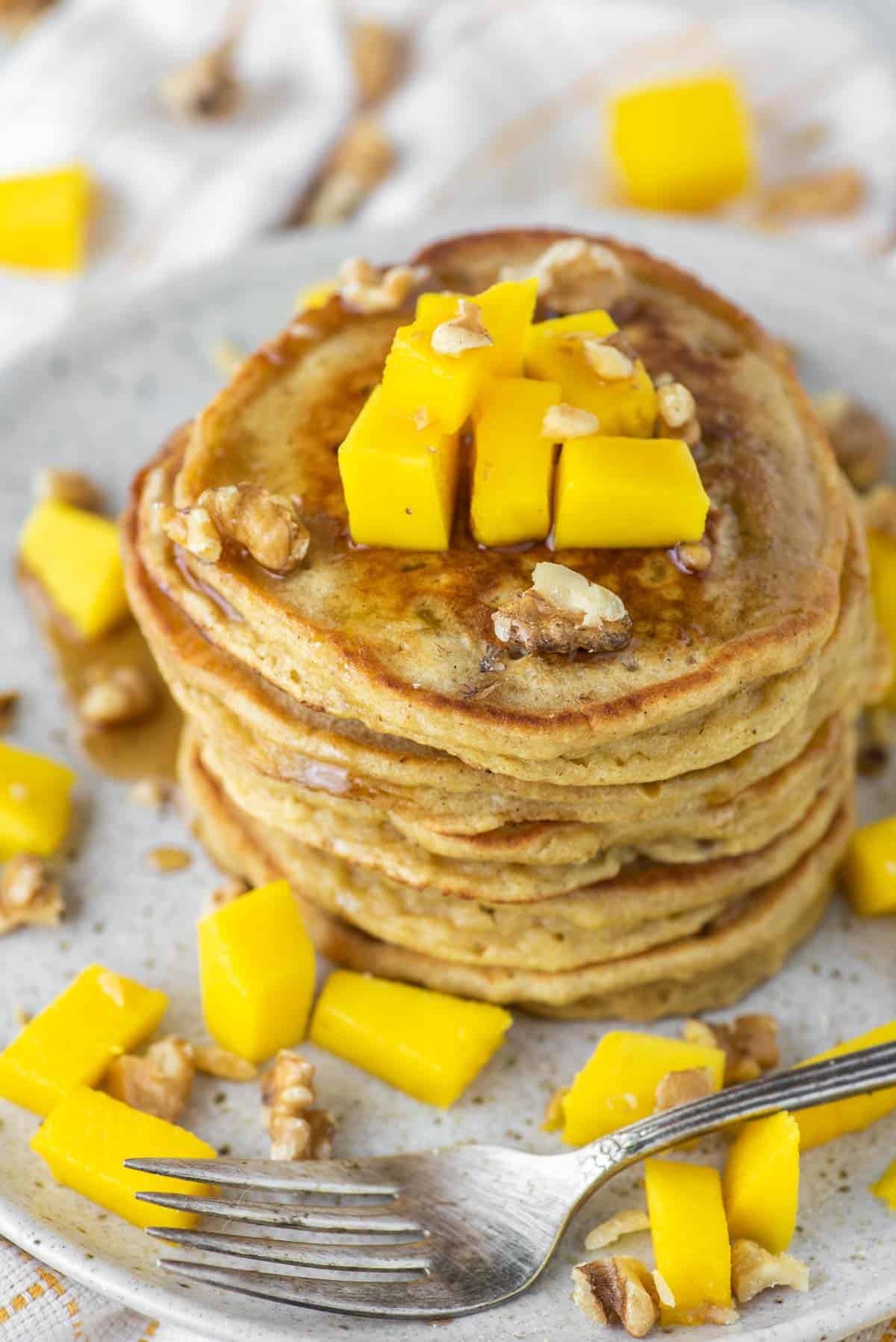 a stack of mango pancakes on plate with fork