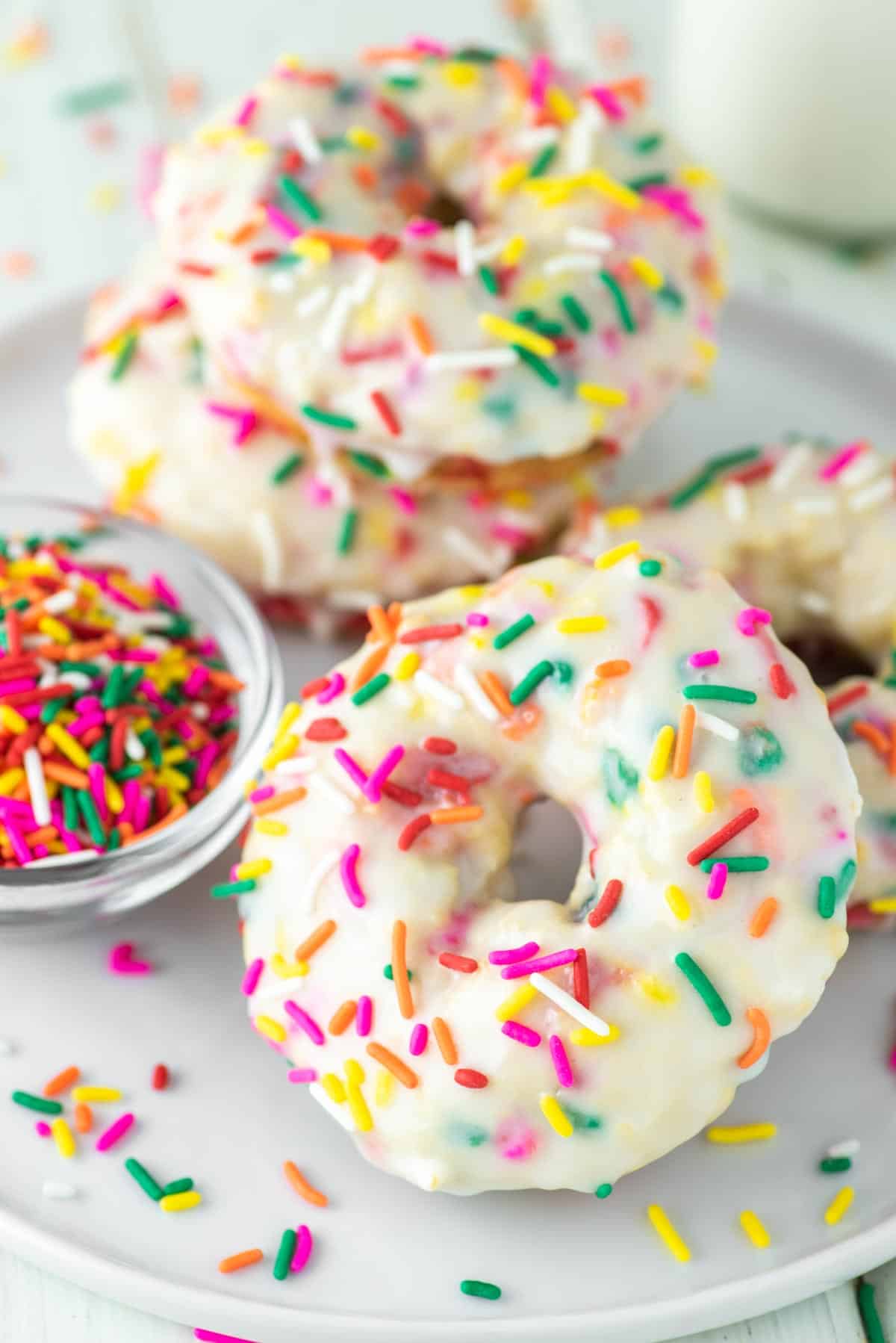 baked vanilla donuts with sprinkles on white plate