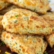 cheddar and chive scones stacked on top of each other on wood board