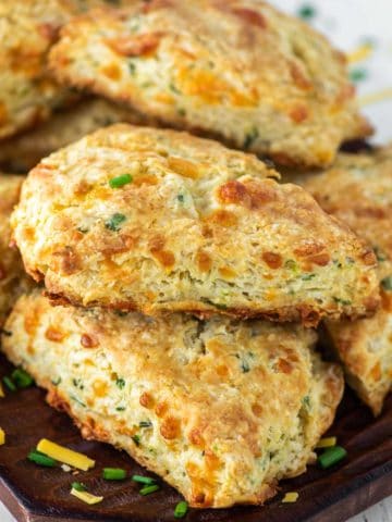 cheddar and chive scones stacked on top of each other on wood board