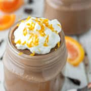 glass jar of chocolate orange mousse with whipped cream and orange zest on top
