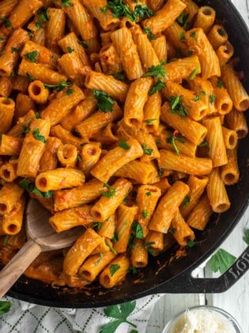 overhead shot of wooden spoon dipped in skillet with spicy rigatoni