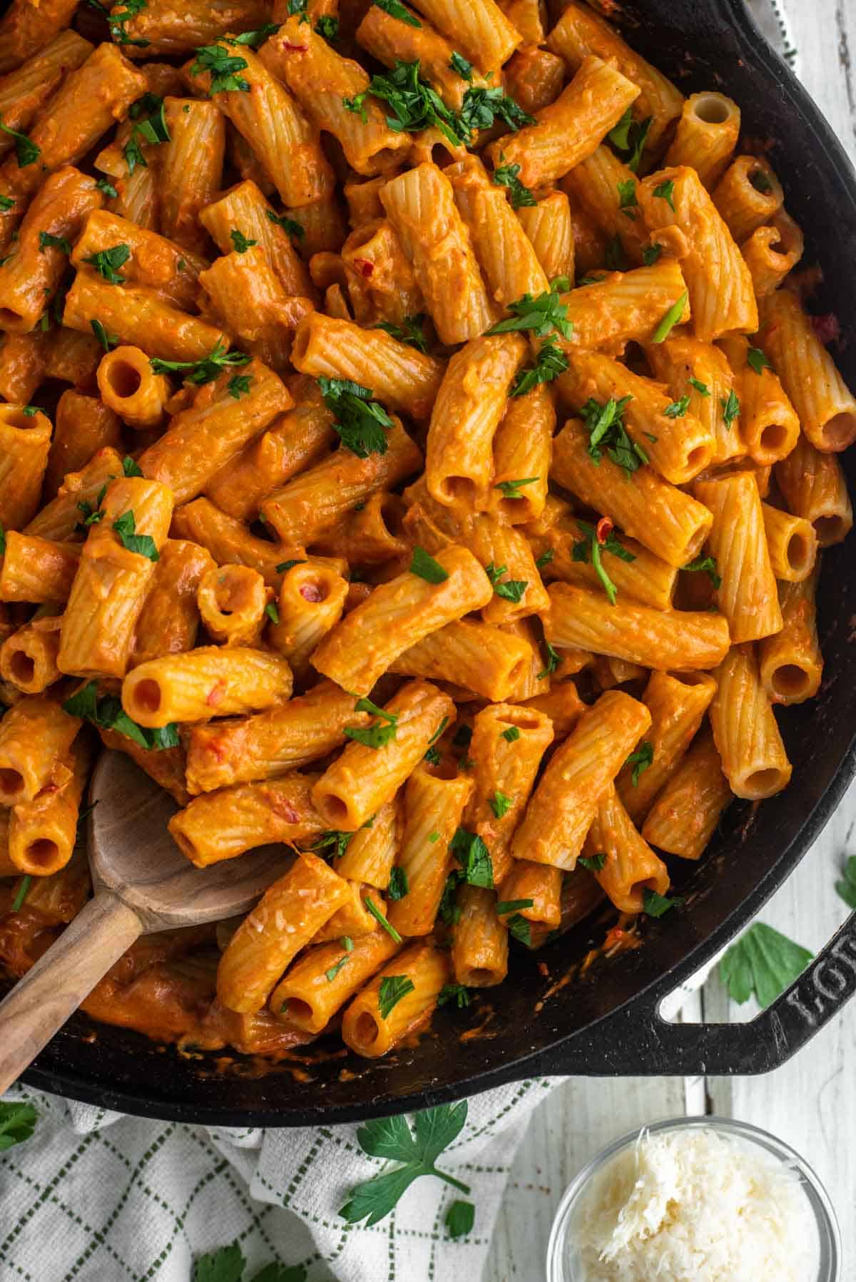 overhead shot of wooden spoon dipped in skillet with spicy rigatoni