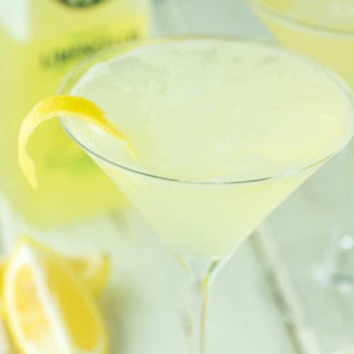 limoncello martini with lemon peel and lemons in background