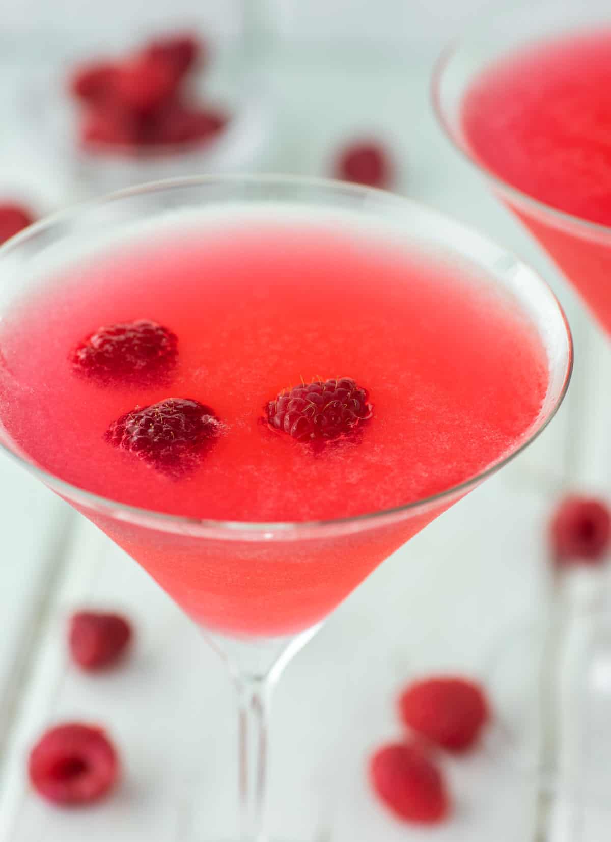 glass of raspberry martini with fresh raspberries in it