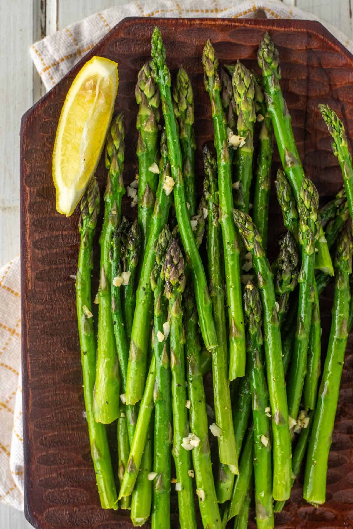 overhead shot of smoked asparagus on wood board with slice of lemon