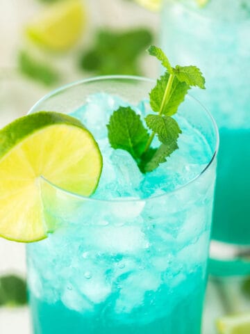close-up of blue mojito in glass with lime and mint