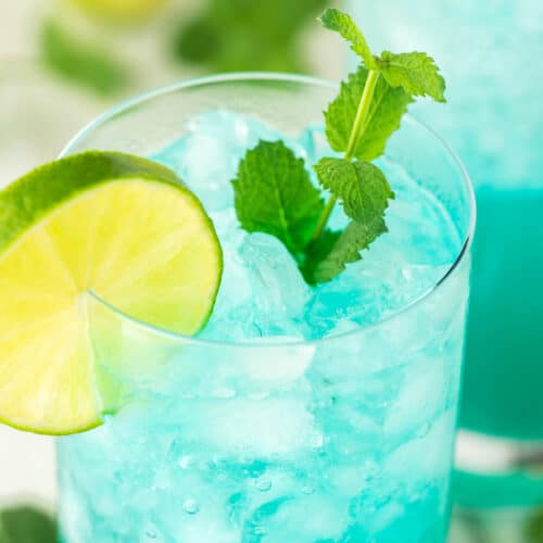 close-up of blue mojito in glass with lime and mint
