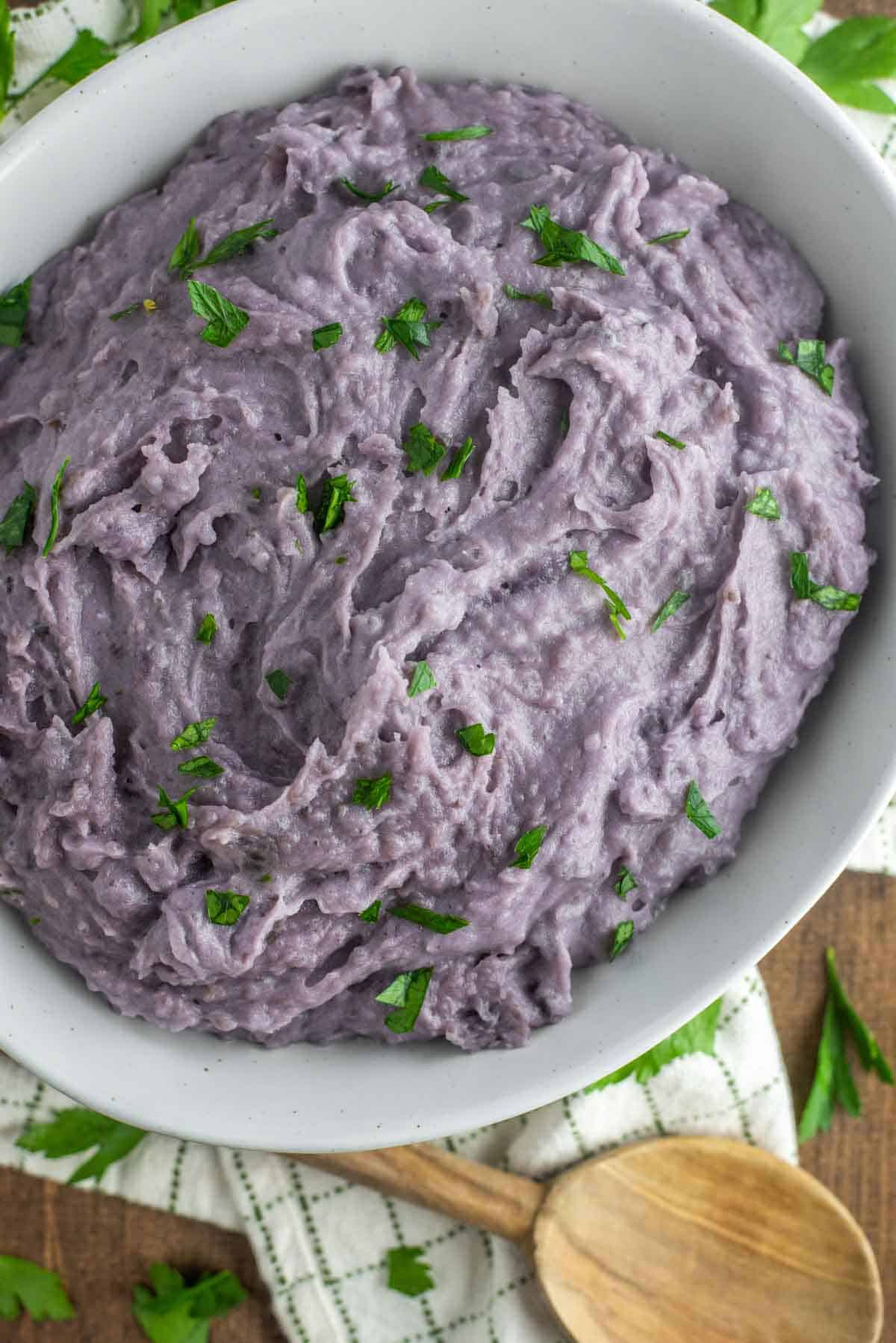 overhead shot of purple mashed potatoes in white bowl