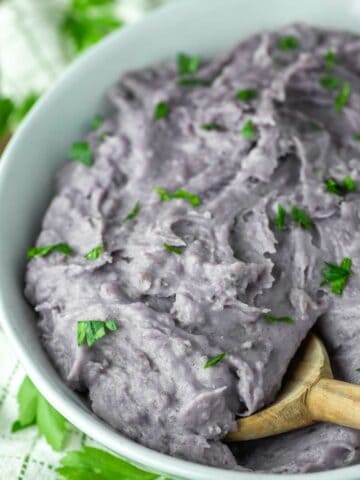 wooden spoon dipped in bowl of purple mashed potatoes