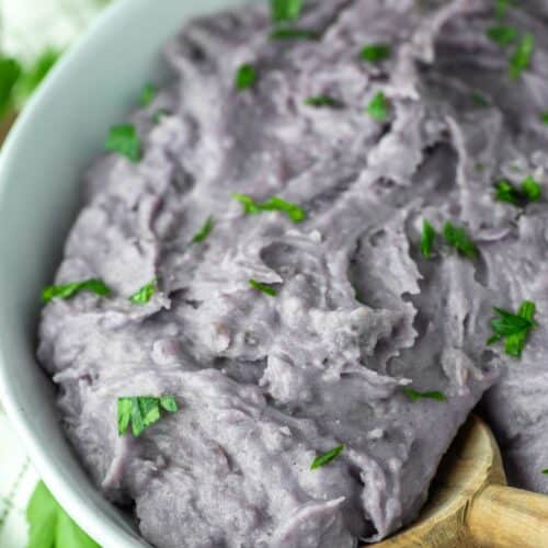 wooden spoon dipped in bowl of purple mashed potatoes