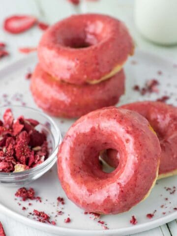 4 strawberry frosted donuts on white plate