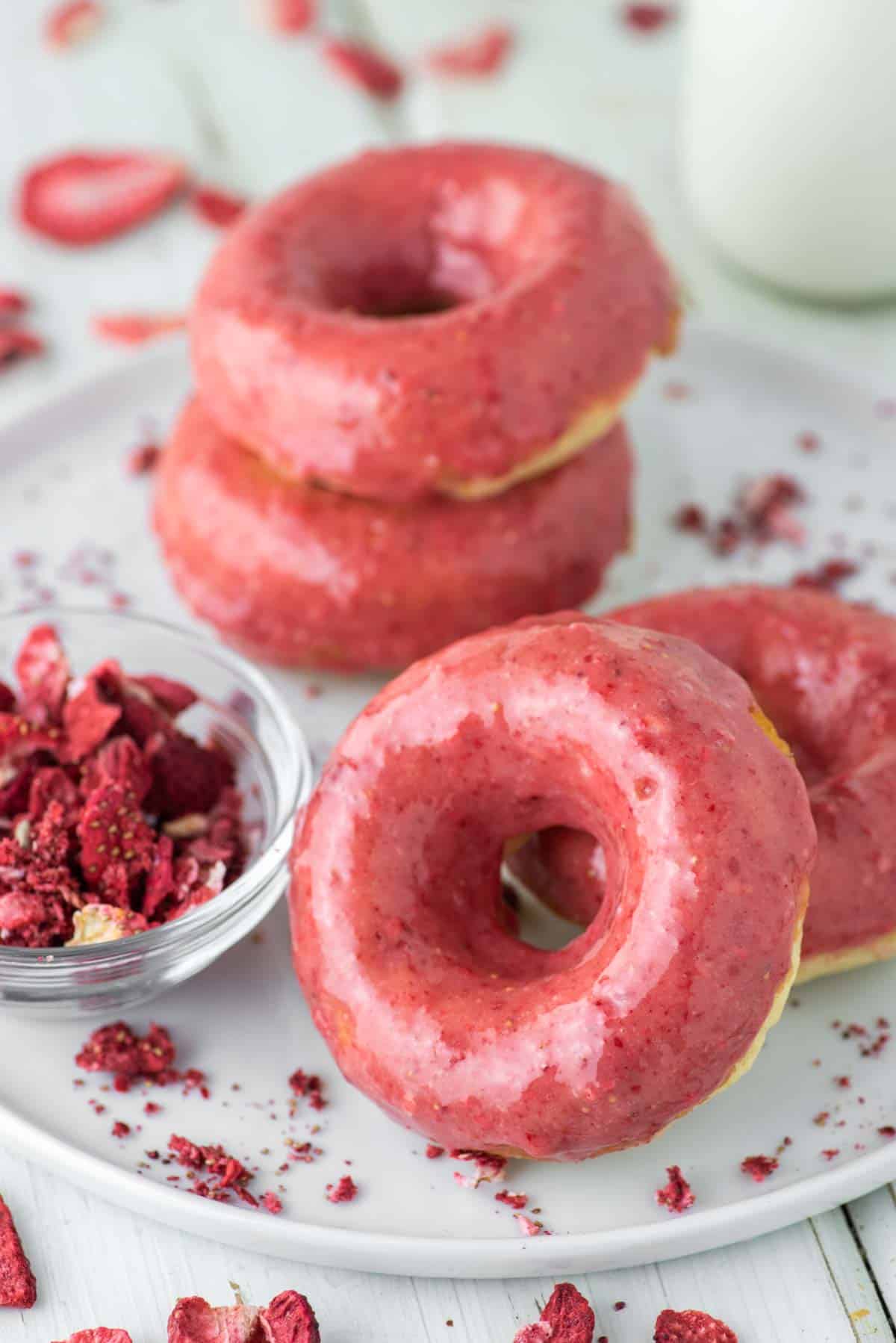 4 strawberry glazed donuts on white plate