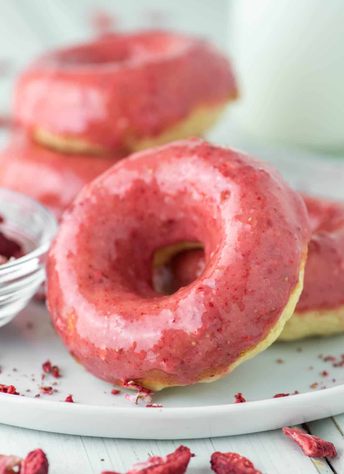 close-up of strawberry glazed donuts on white plate