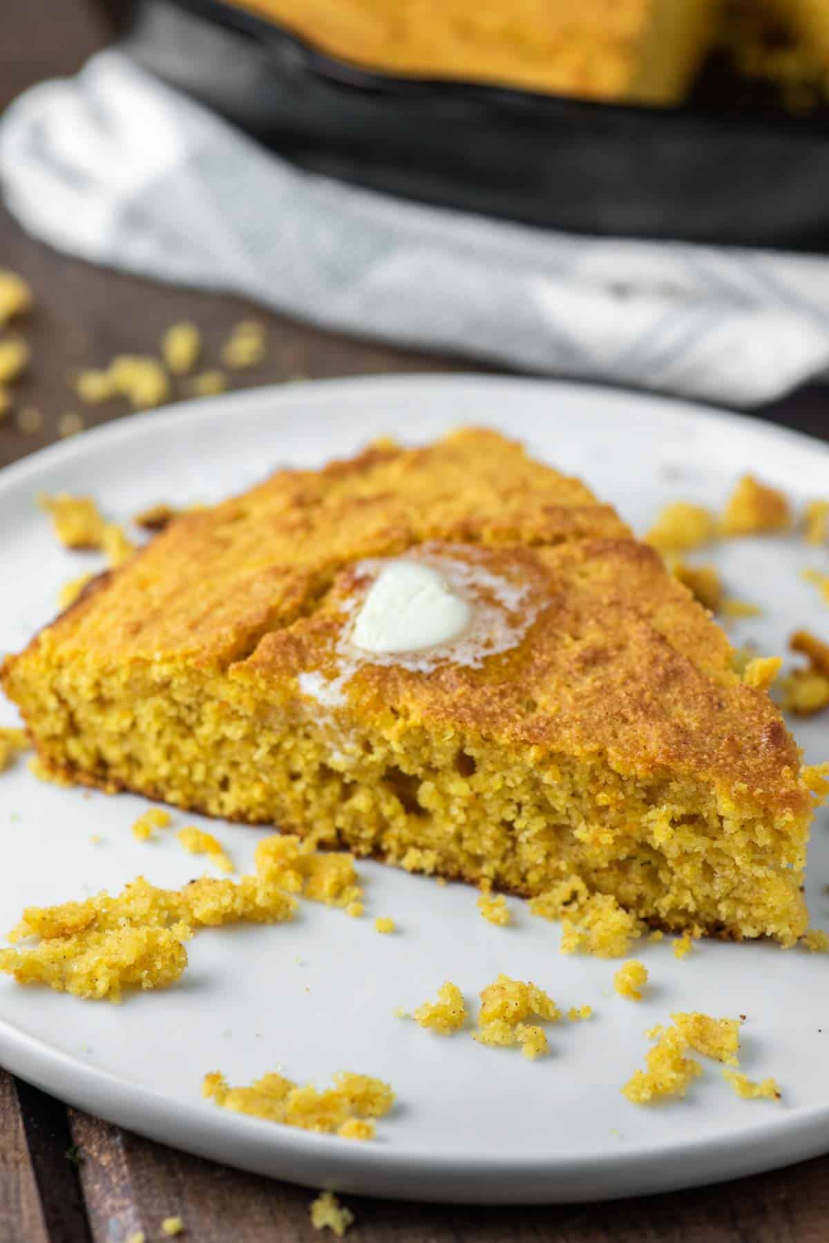 slice of sweet potato cornbread on white plate with butter