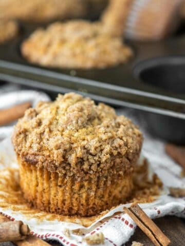 cinnamon streusel muffin with cupcake liner removed and more in background