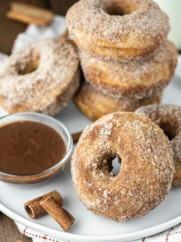 churro donuts on white plate with bowl of chocolate sauce