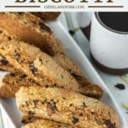 amaretto biscotti on white plate with cup of coffee in background