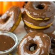 baked pumpkin donuts with chocolate glaze on plate with pumpkins in the background