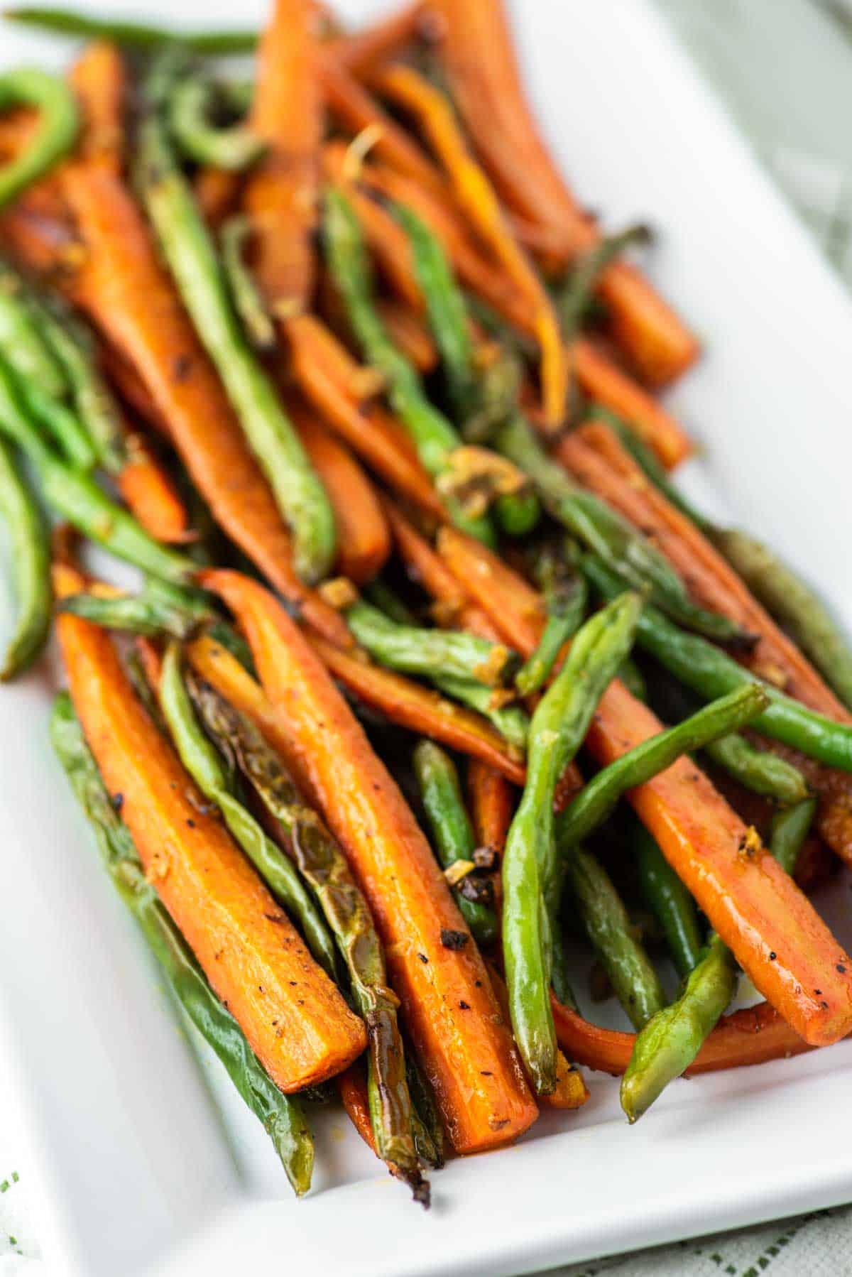 roasted carrots and green beans on white rectangle plate