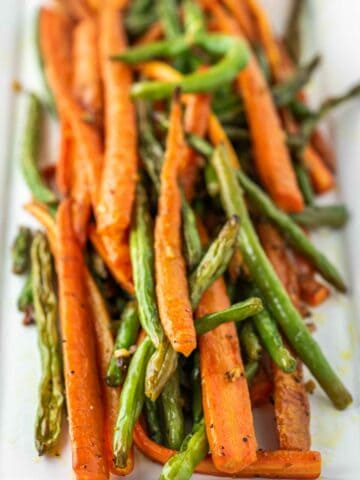 close-up of roasted carrots and green beans on white plate