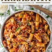 overhead shot of rigatoni arrabbiata in bowl with wooden spoon