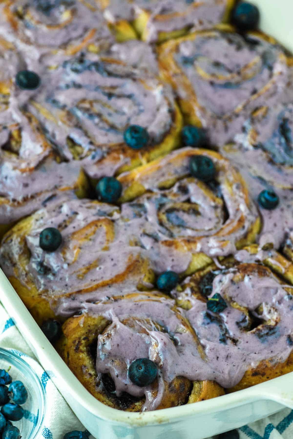close-up of blueberry cinnamon rolls in white baking dish