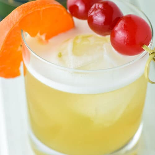 close-up of Jameson whiskey sour in old fashioned glass with cherries and orange slice