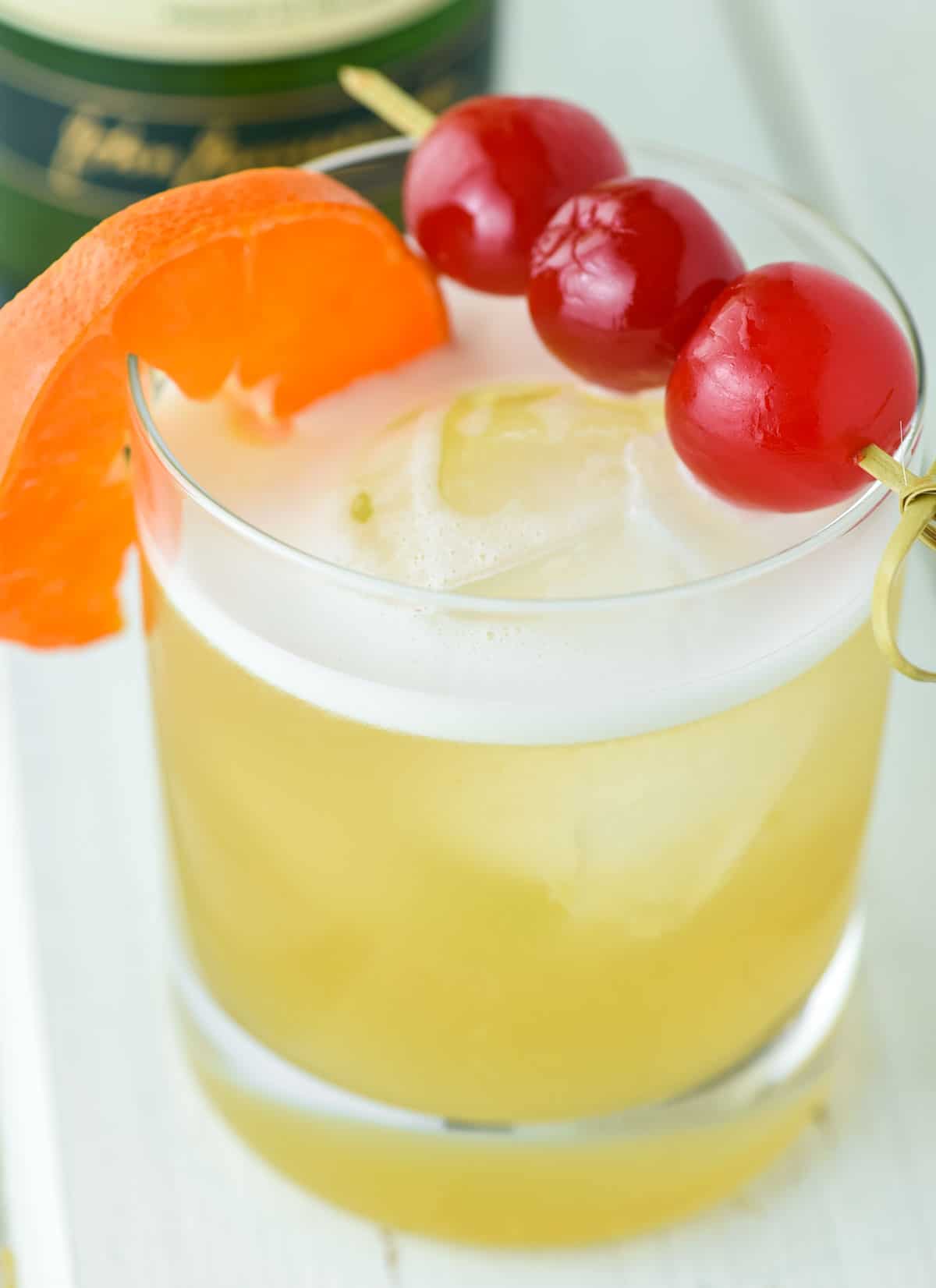 close-up of Jameson whiskey sour in old fashioned glass with cherries and orange slice