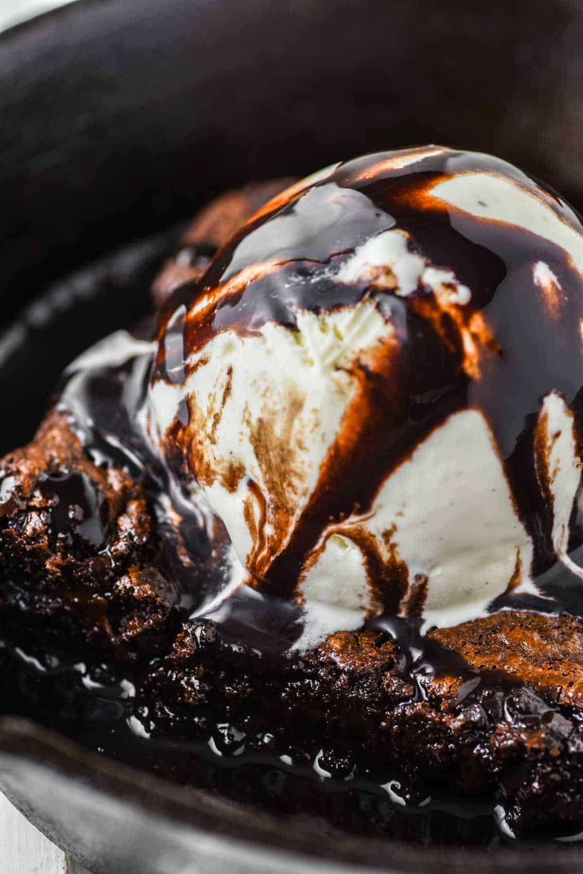 close-up of sizzling brownie topped with ice cream in cast iron skillet