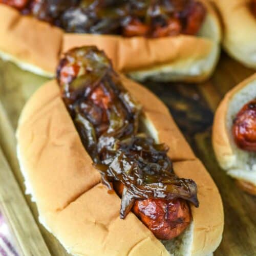 close-up of smoked brats with beer onions on wood board