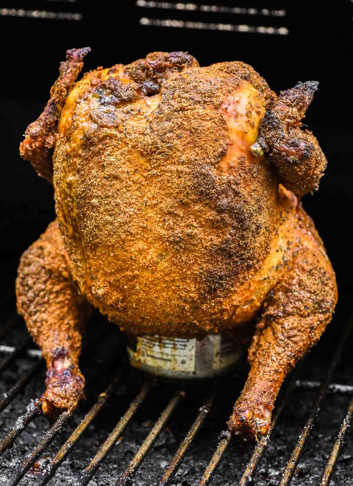 smoked chicken sitting on beer in smoker