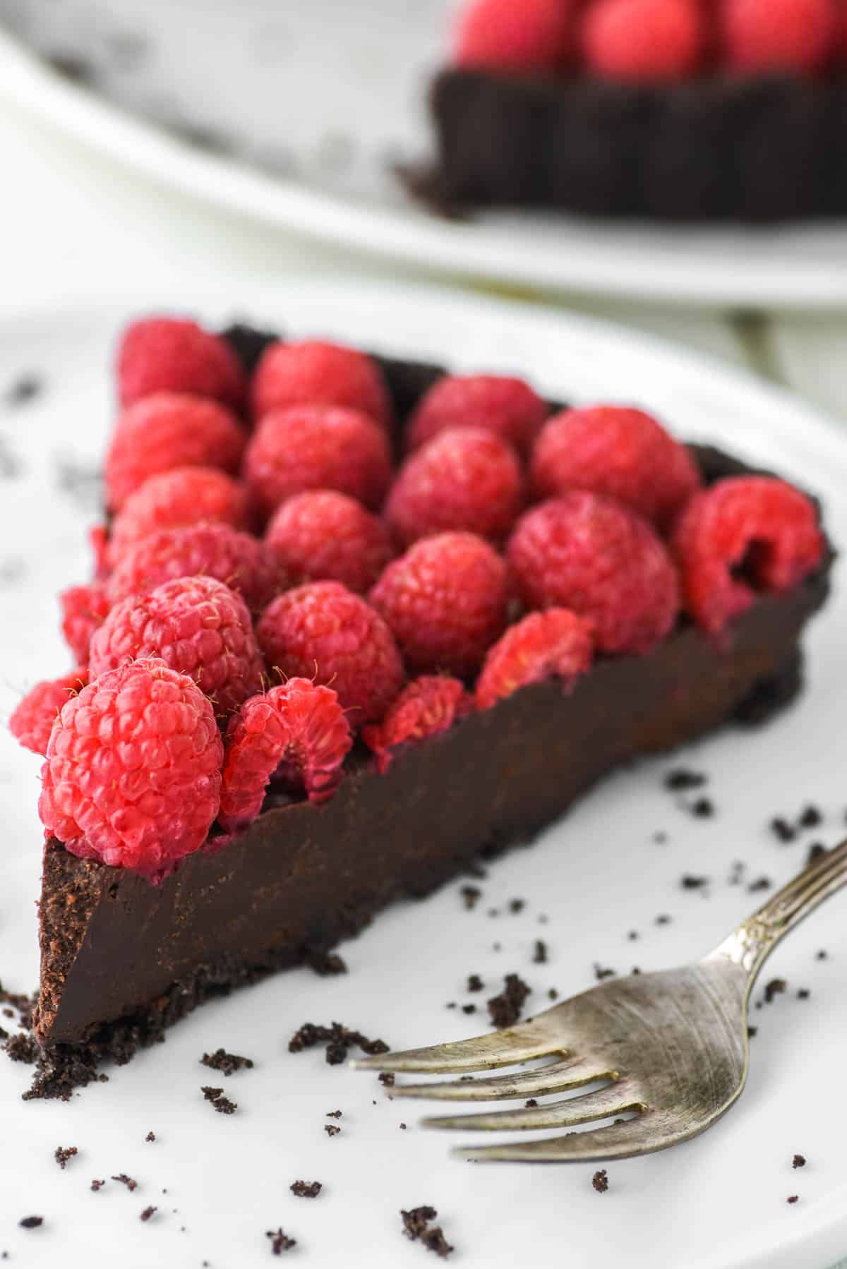 close-up of slice of chocolate raspberry tart on plate with fork