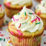 funfetti cupcakes with white frosting and sprinkles on white board
