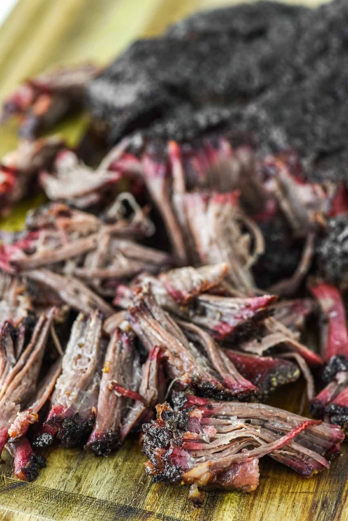 close-up of smoked pulled beef on wood cutting board