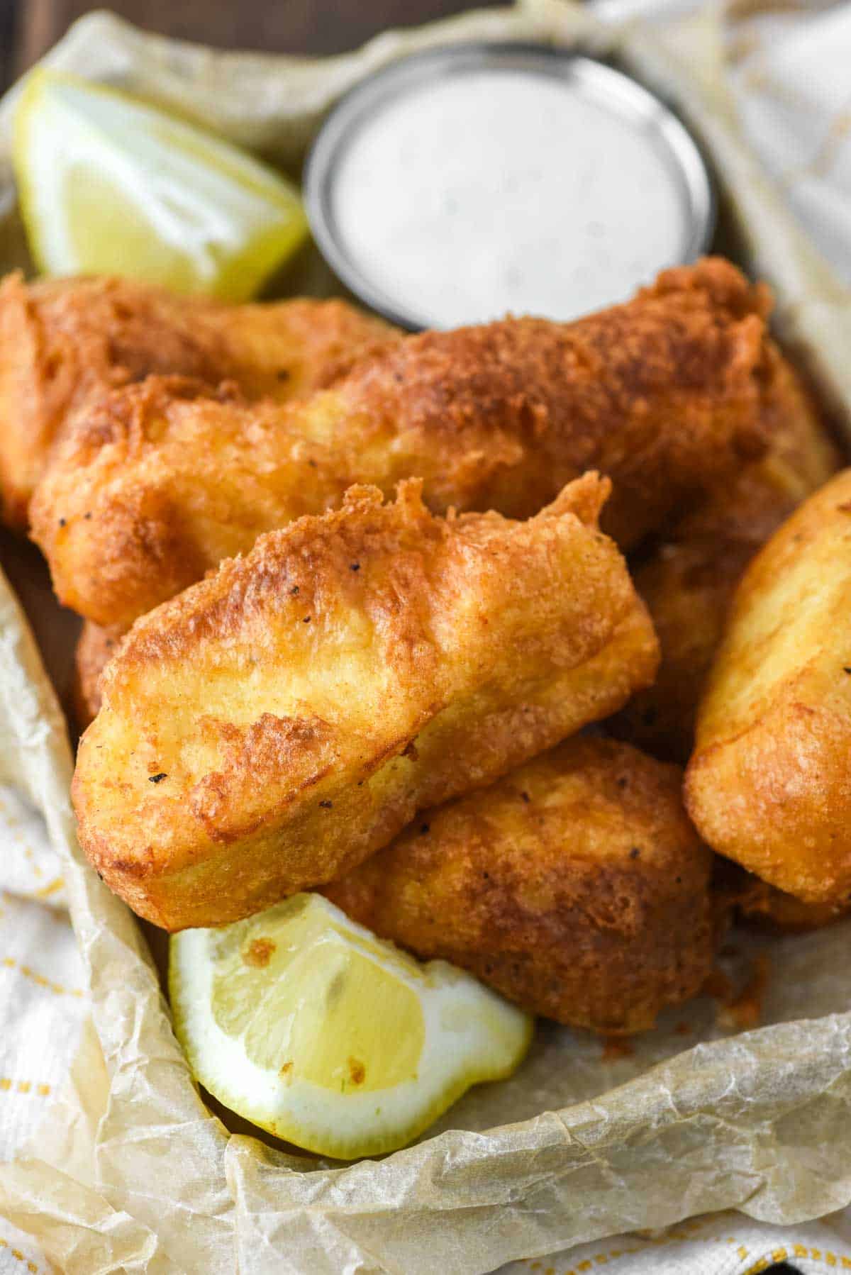 close-up of beer battered halibut in metal tin lined with parchment paper