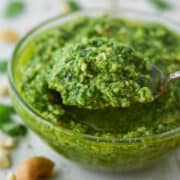 close-up of spoon lifting out pesto from glass bowl