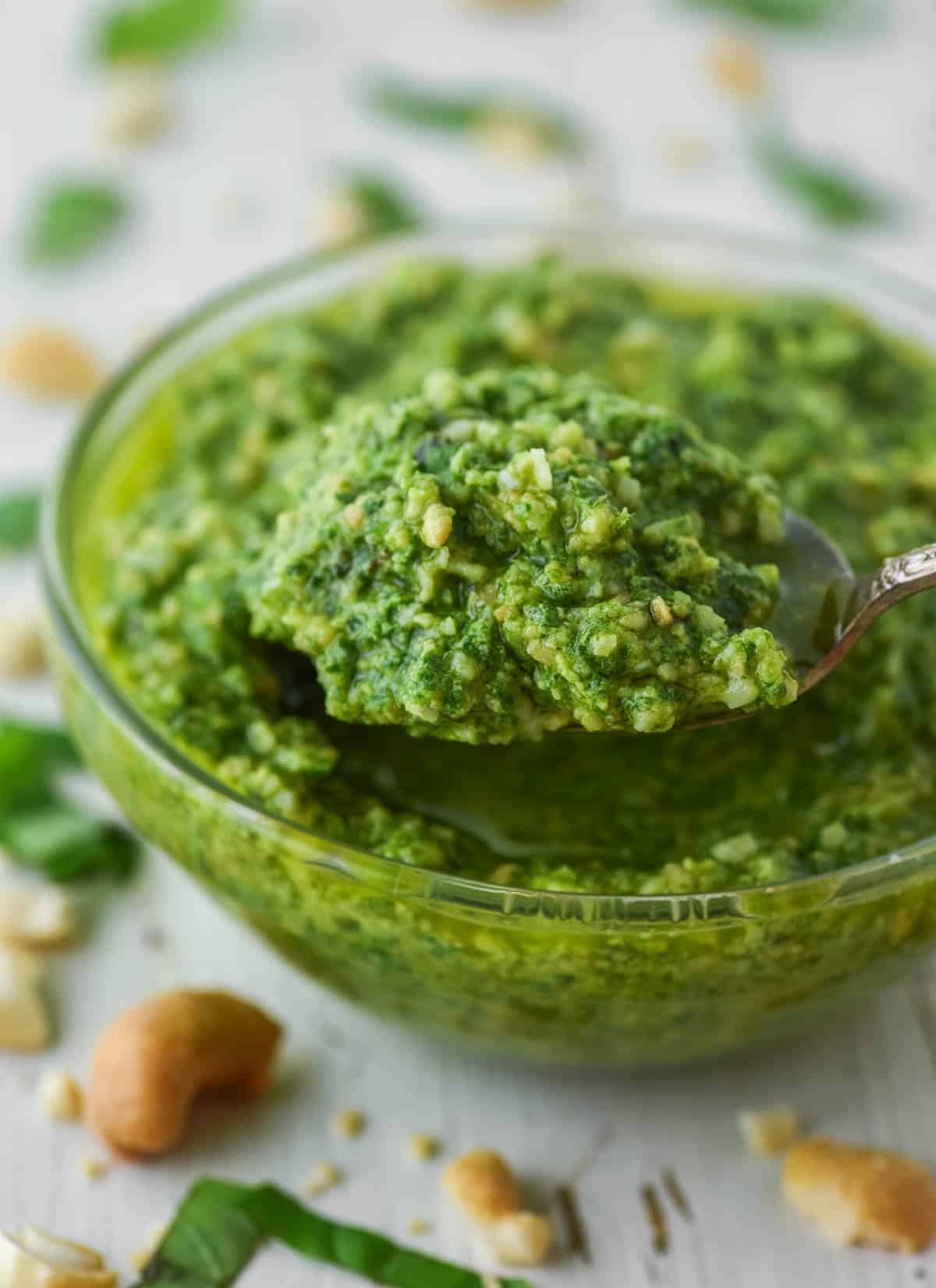 close-up of spoon lifting out pesto from glass bowl