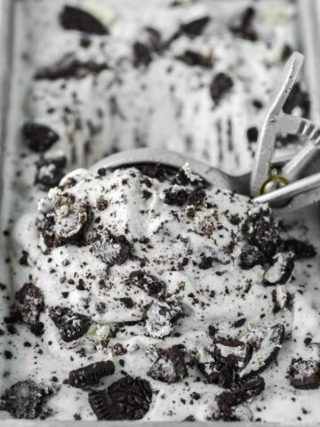 Oreo ice cream being scooped out of metal tin by ice cream scoop