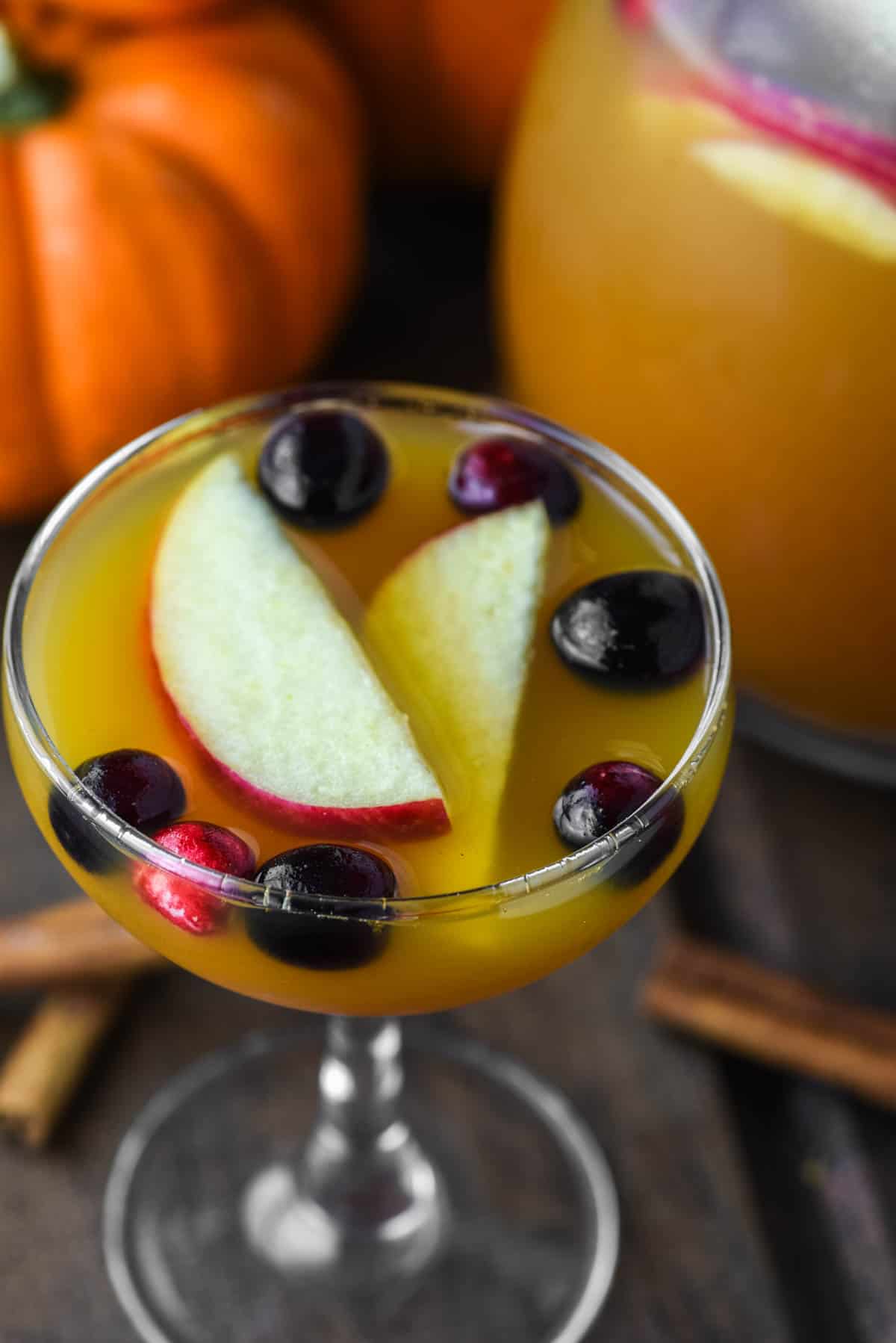 close-up of glass of pumpkin punch with pitcher and pumpkins in background