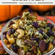 glass bowl of pumpkin spice granola with pumpkins behind it