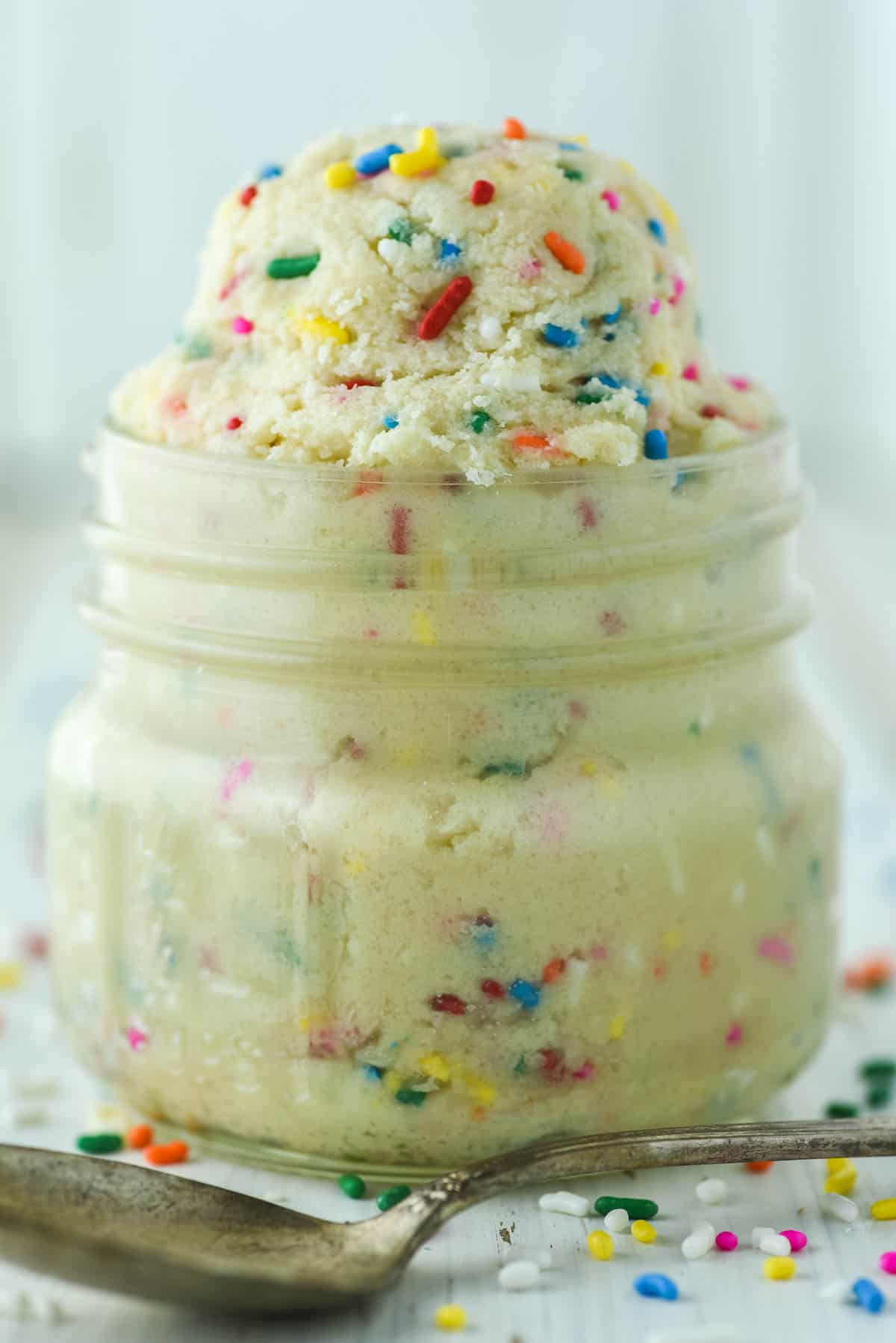close-up of edible sugar cookie dough in mason jar with spoon in front