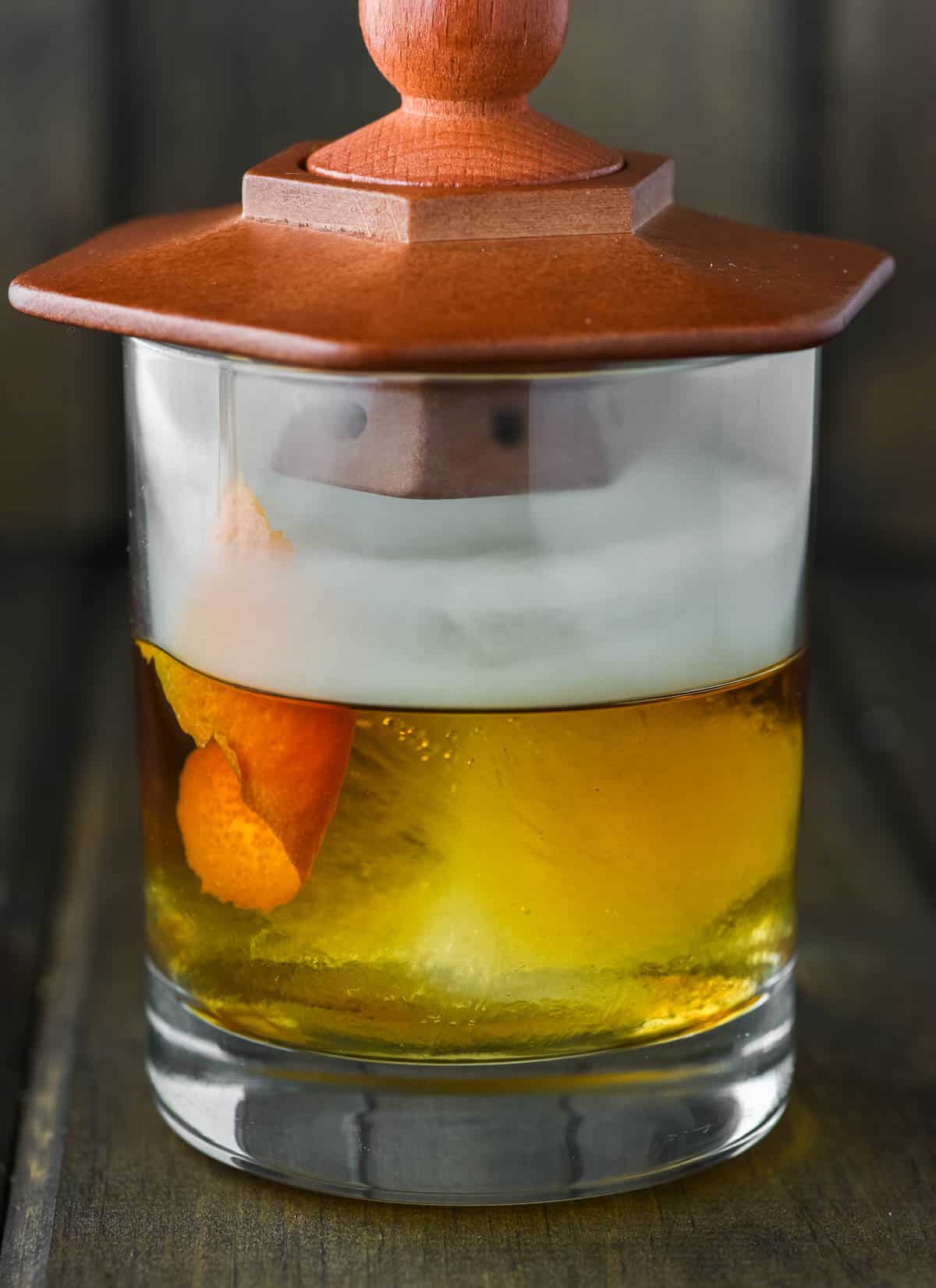 cocktail smoker on top of glass of old fashioned adding smoke flavor