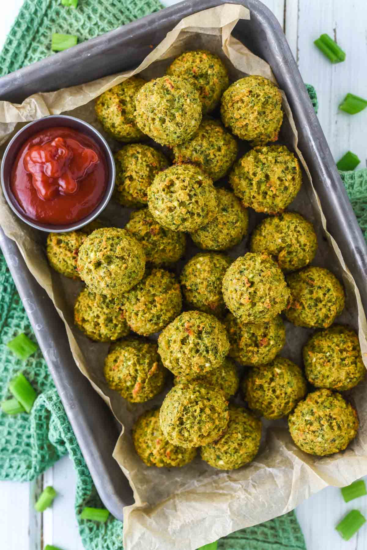overhead shot of broccoli bites in parchment-lined tin
