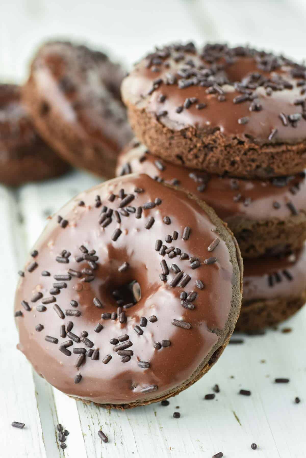 close-up of double chocolate donut leaning against a stack of donuts