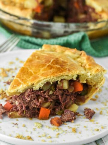 slice of corned beef pie on white plate with dish in background